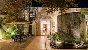 An outdoor patio with a stone table and chairs, a water feature, and a staircase leading to an upper level. - Verde Morada Hotel Encuentro (Valladolid)