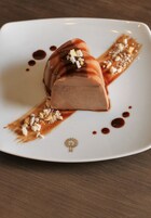 Un postre en un plato blanco con salsa de caramelo y nueces desmenuzadas.