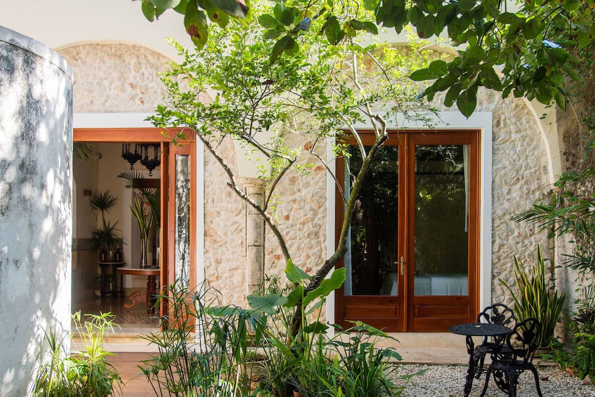 A garden with a wooden deck, potted plants, and a stone wall.