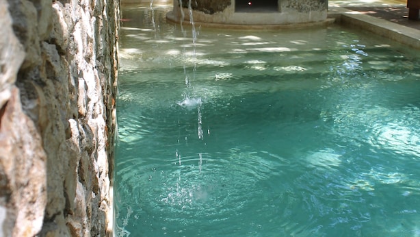 A clear pool with a stone wall and a small structure with a door. - Verde Morada Hotel Encuentro (Valladolid)