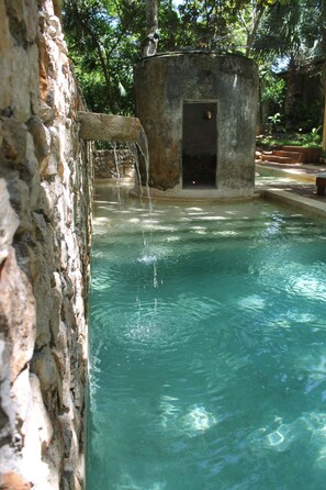 A clear pool with a stone wall and a small structure with a door. - Verde Morada Hotel Encuentro (Valladolid)