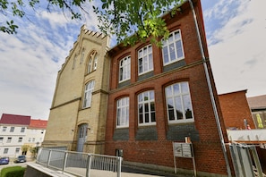 A two-story building with a red brick facade and a beige tower.
