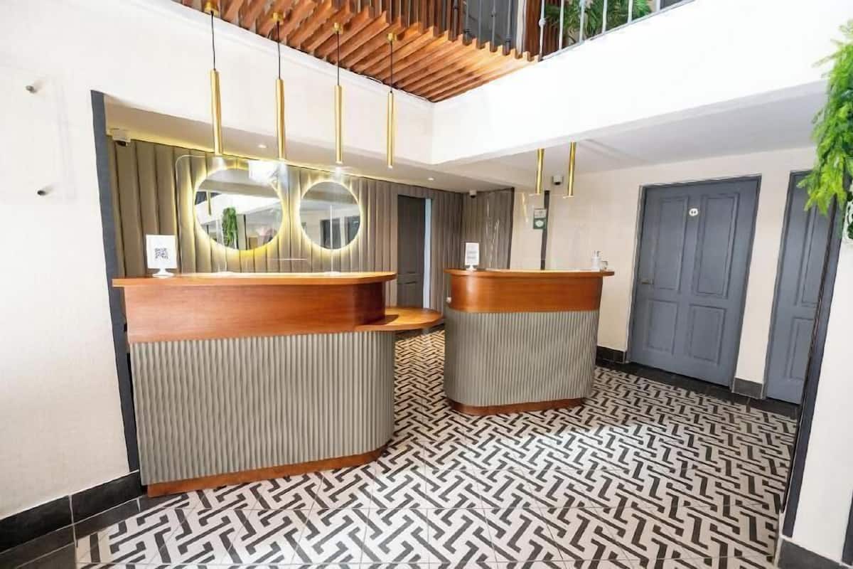A reception area with two wooden reception desks, a patterned floor, and a ceiling with wooden slats.