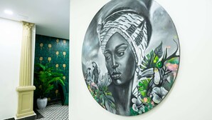 A hallway with a patterned floor and a large circular artwork featuring a woman and parrots. - Gran Hotel Europa Santo Domingo, Trademark by Wyndham (Santo Domingo)
