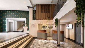 A hotel lobby with a geometric patterned floor, a reception desk, a staircase, and a view of the upper floor. - Gran Hotel Europa Santo Domingo, Trademark by Wyndham (Santo Domingo)