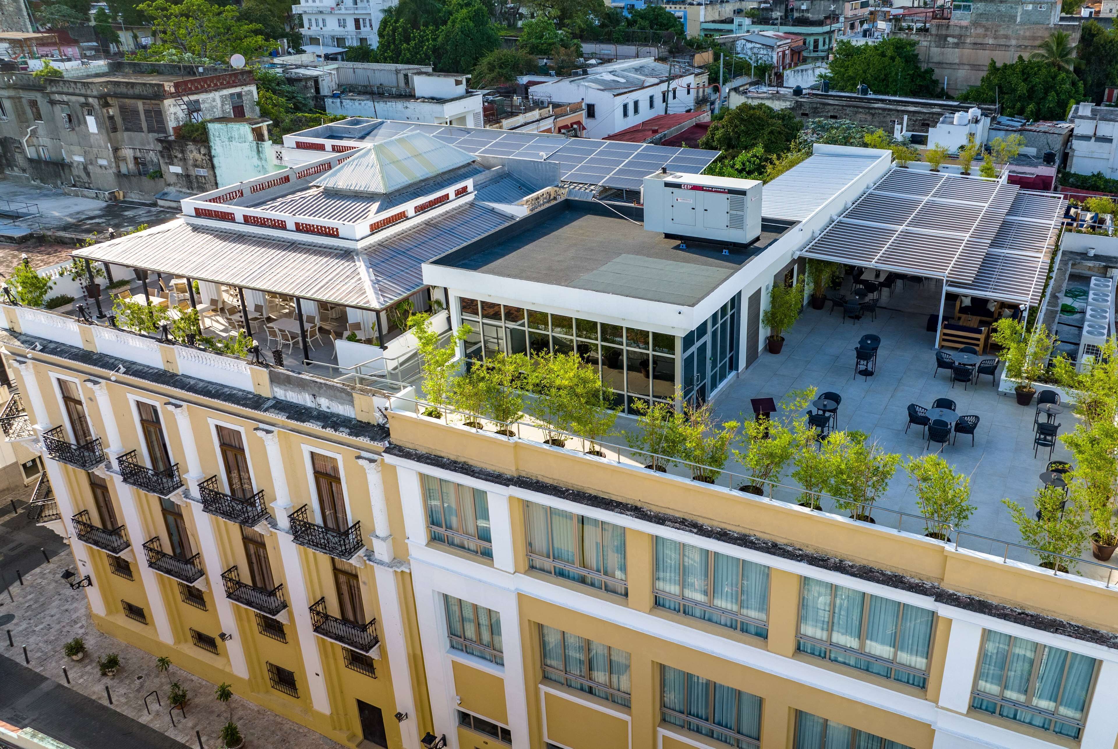 A multi-story building with balconies, a rooftop terrace with solar panels, and outdoor seating areas.