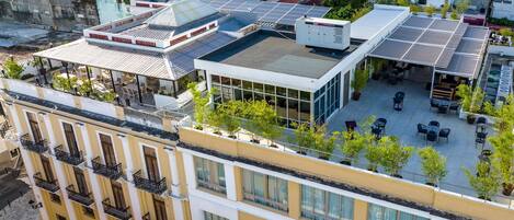 A multi-story building with balconies, a rooftop terrace with solar panels, and outdoor seating areas.