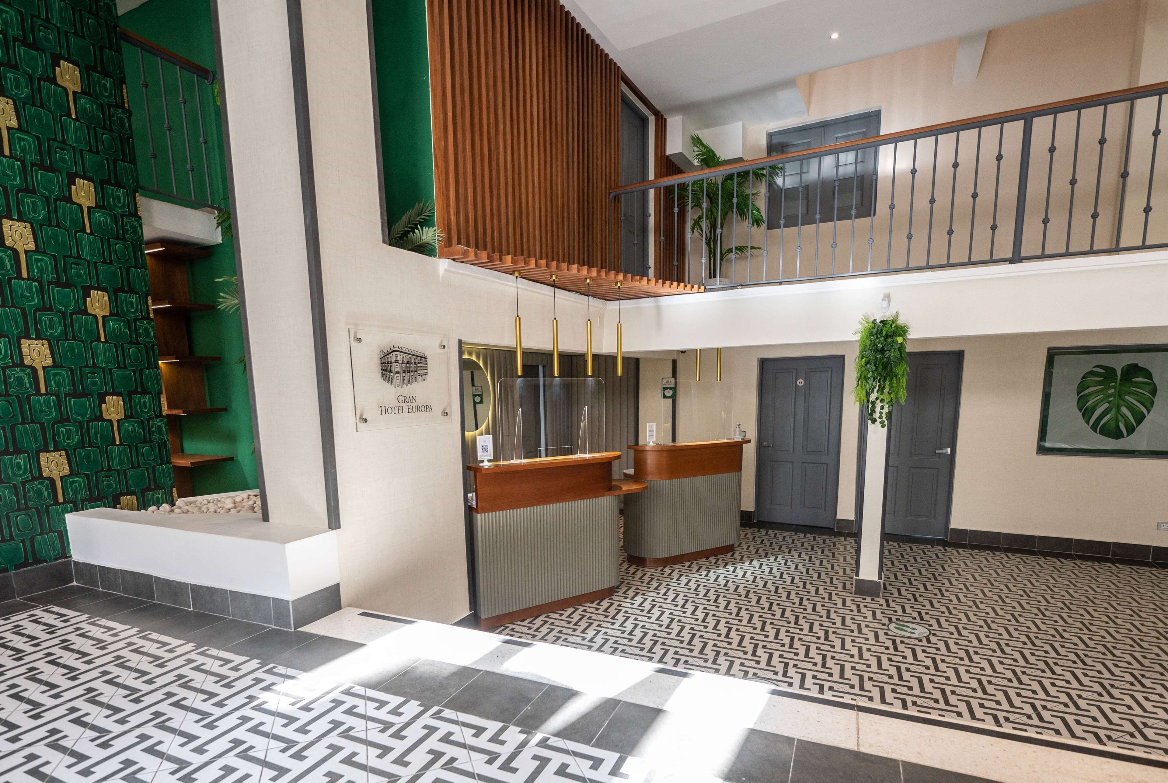 Un vestíbulo de hotel con mostrador de recepción, una escalera y un suelo estampado.