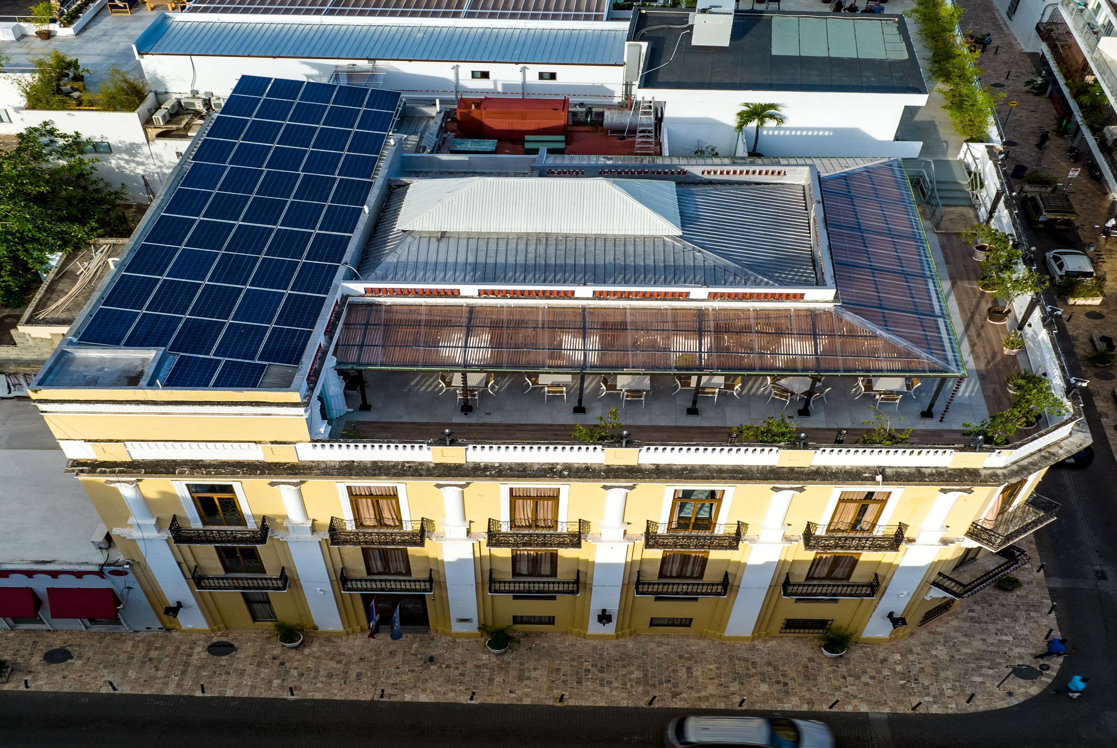 A building with a rooftop covered in solar panels, a central courtyard with seating, and a traditional facade with balconies.