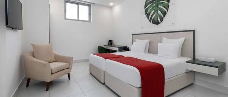 A modern bedroom with a bed, bedside tables, a chair, and a large plant.