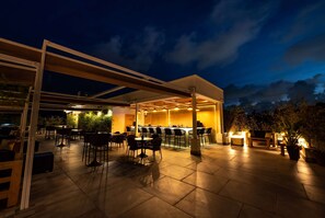 An outdoor patio area with tables and chairs, a bar, and potted plants. - Gran Hotel Europa Santo Domingo, Trademark by Wyndham (Santo Domingo)