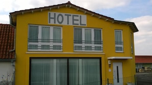 En gul bygning med et skilt, der siger "HOTEL" over indgangen.