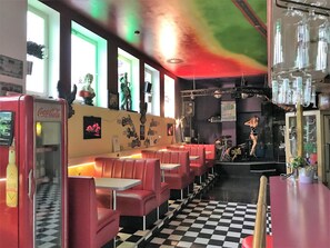 A diner with red booths, a checkered floor, and a stage for live music. - Hotel Route 84 (Bad Langensalza)