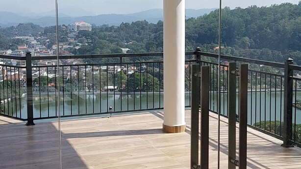 Un balcón amplio con vistas despejadas a un lago y edificios lejanos.
