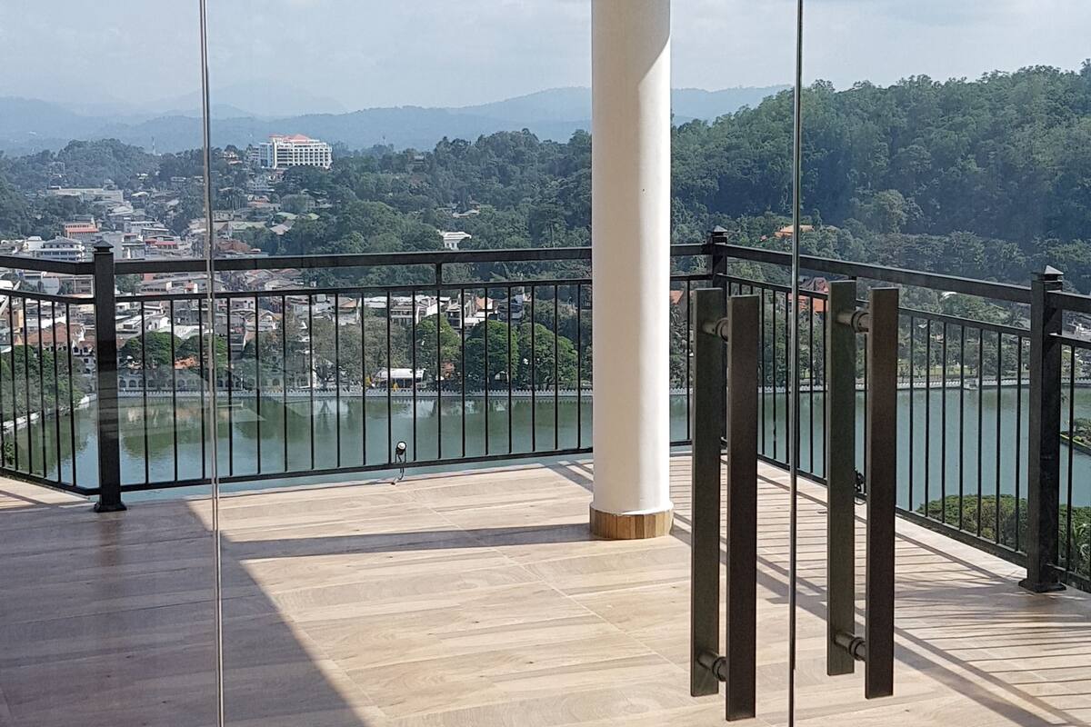 A spacious balcony with a clear view of a lake and distant buildings.