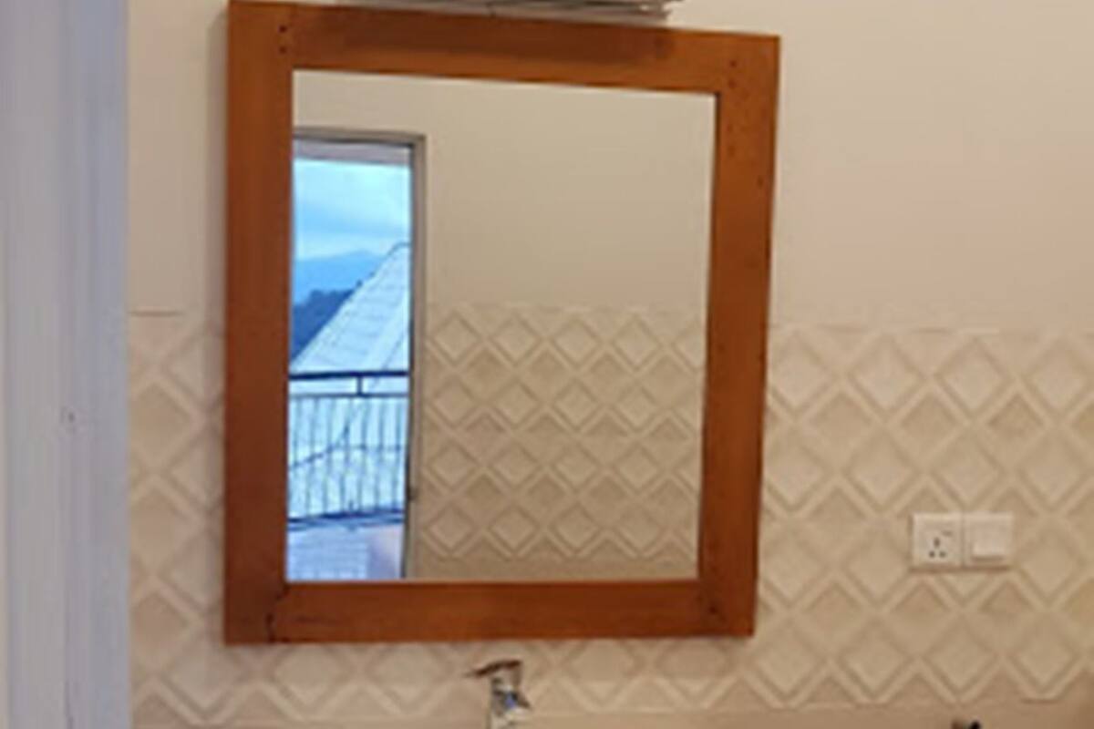 A bathroom with a white sink, wooden-framed mirror, and patterned wall tiles.