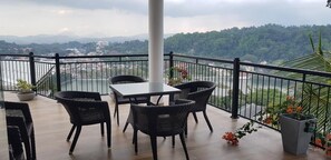 Ein Balkon mit Korbmöbeln, einem weißen Tisch und Topfpflanzen.