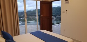 Ein Hotelzimmer mit Bett, Blick auf einen Balkon und einer Tür, die nach draußen führt.