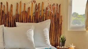 Una cama con almohadas blancas, una colcha de estilo azul y amarillo, y una pared de madera con troncos verticales.