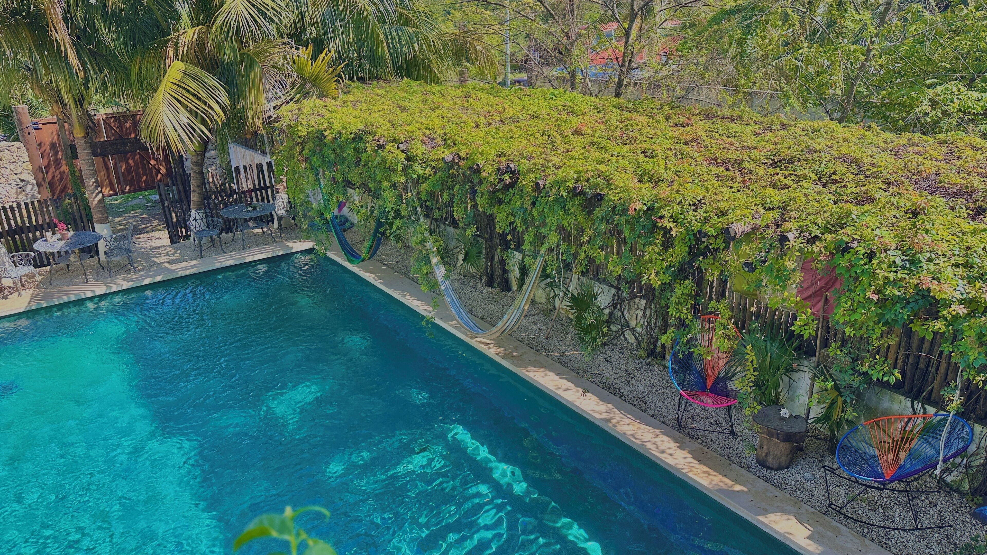 Piscina com jardim ao redor e área de estar.