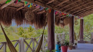 Un espacio al aire libre cubierto con una hamaca, barandas de madera y plantas en macetas.