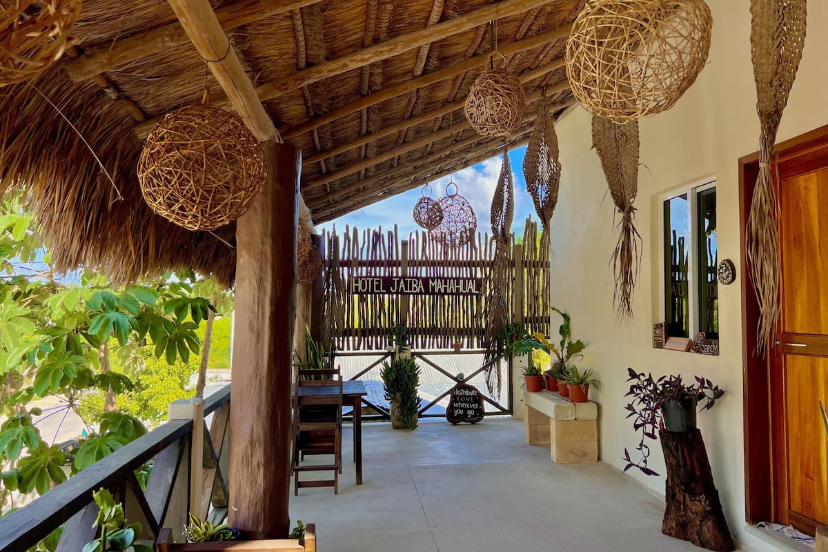 Un espace extérieur abrité, doté d’une clôture en bois, de plantes en pot et de décorations suspendues en osier.