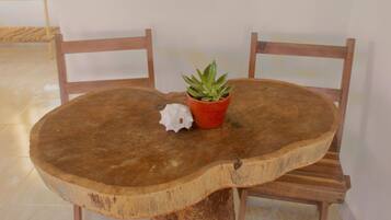 A round wooden table with a natural finish, accompanied by two wooden chairs. A small potted plant and a decorative object are placed on the table.