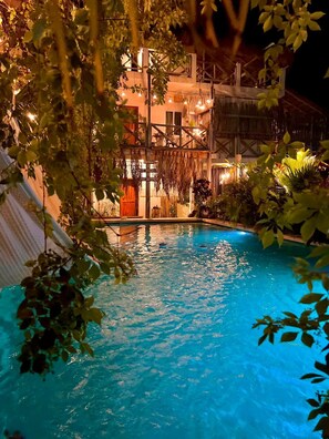 A swimming pool surrounded by lush greenery and a building with a rustic design. - Hotel Jaiba Mahahual (Mahahual)