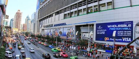 A busy urban street with a large building featuring a sign for a fashion mall.