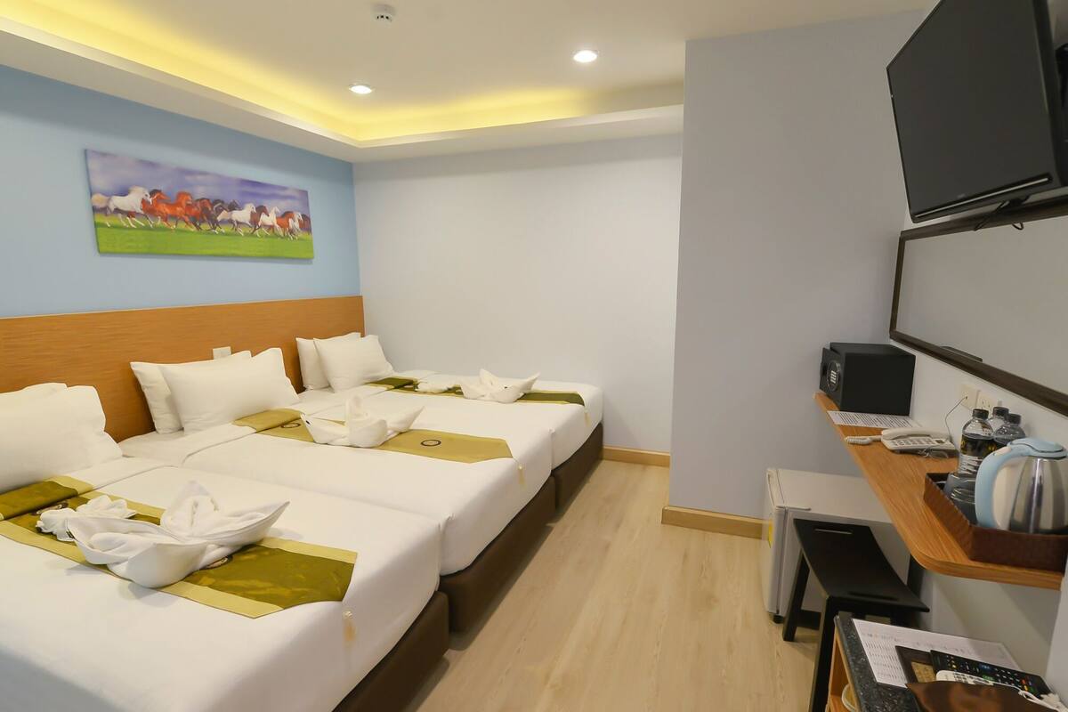 A hotel room with two beds, a desk with a computer, a TV, and a painting on the wall.
