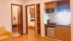 Un ambiente compatto con angolo cottura, un piccolo frigorifero e un letto nella stanza adiacente.