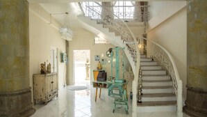Un vestíbulo amplio con una escalera blanca, un candelabro y vistas al piso superior.