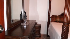 A bedroom with a wooden four-poster bed, a nightstand, a dresser, and a mirror. - Oaklands Apartment complex (Kingston)