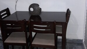 A dining area with a table, four chairs, a decorative bowl, and a flat-screen TV mounted on the wall. - Oaklands Apartment complex (Kingston)