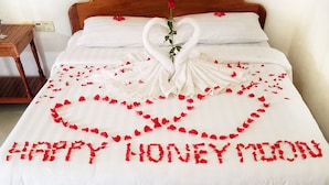 A bed with a heart-shaped arrangement of rose petals spelling "HAPPY HONEYMOON" and a swan made of fabric. - Angkor Bosky Hotel (Siem Reap)