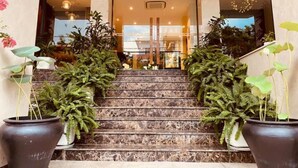 A hotel entrance with marble stairs, potted plants on either side, and an exit sign above the door. - DaNang Moon Villa & Apartment (Da Nang)