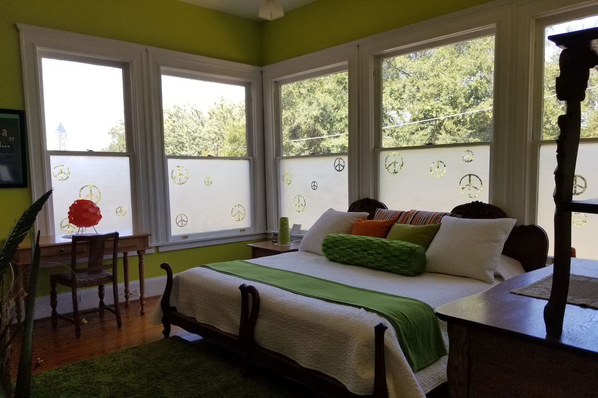 A bedroom with a bed, a chair, and a window with a view of trees.