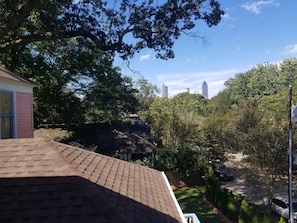 A residential area with a house, trees, and a clear view of distant buildings. - The Peach House (Atlanta)