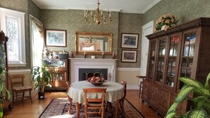 A dining room with a fireplace, a chandelier, and a large wooden cabinet.