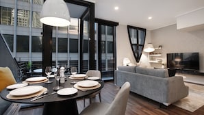 Una sala de estar moderna con comedor, ventanas amplias y un televisor de pantalla plana.
