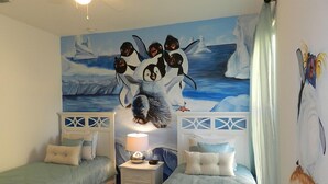 A bedroom with two beds, a nightstand with a lamp, and a mural of penguins on the wall. - Sm215701 - Watersong - 5 Bed 4 Baths Villa (Davenport)