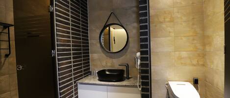 A modern bathroom with a black sink, a round mirror, and a toilet.