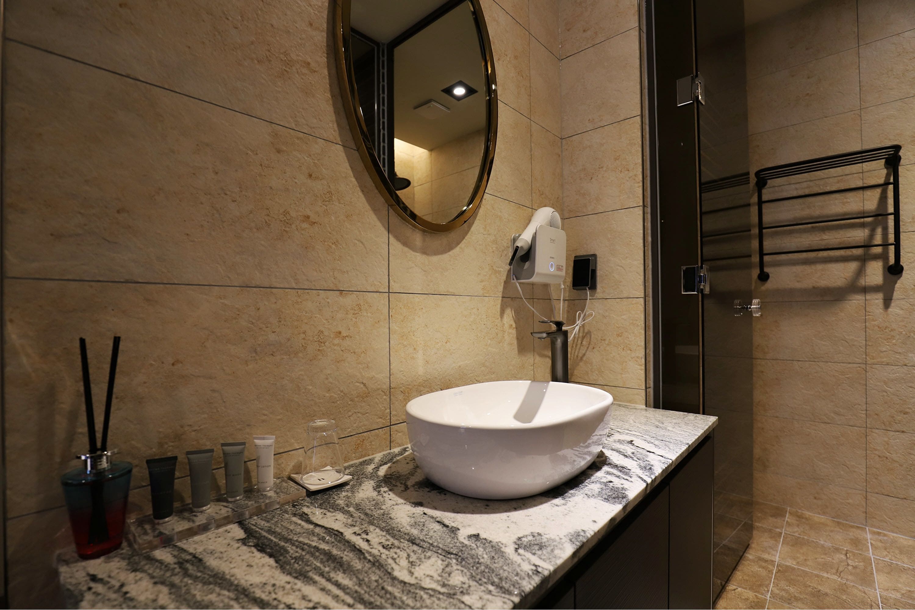 A bathroom with a marble sink, a mirror, and a towel rack.