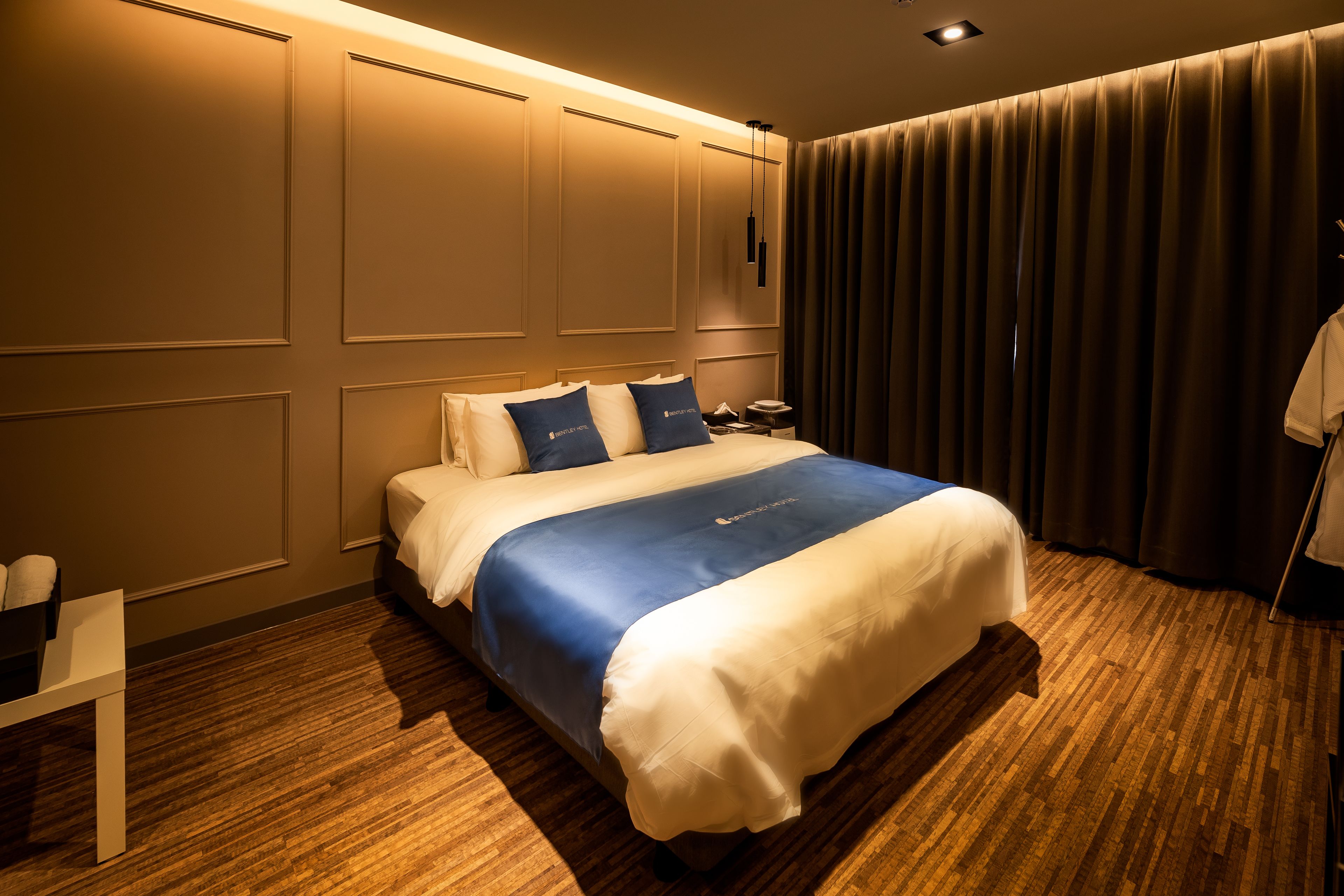 A hotel room with a large bed, a bedside table, a lamp, and a curtain.
