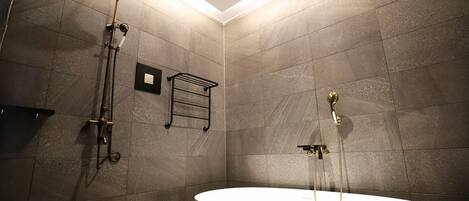 A modern bathroom with a freestanding bathtub, a handheld showerhead, and a wall-mounted towel rack.