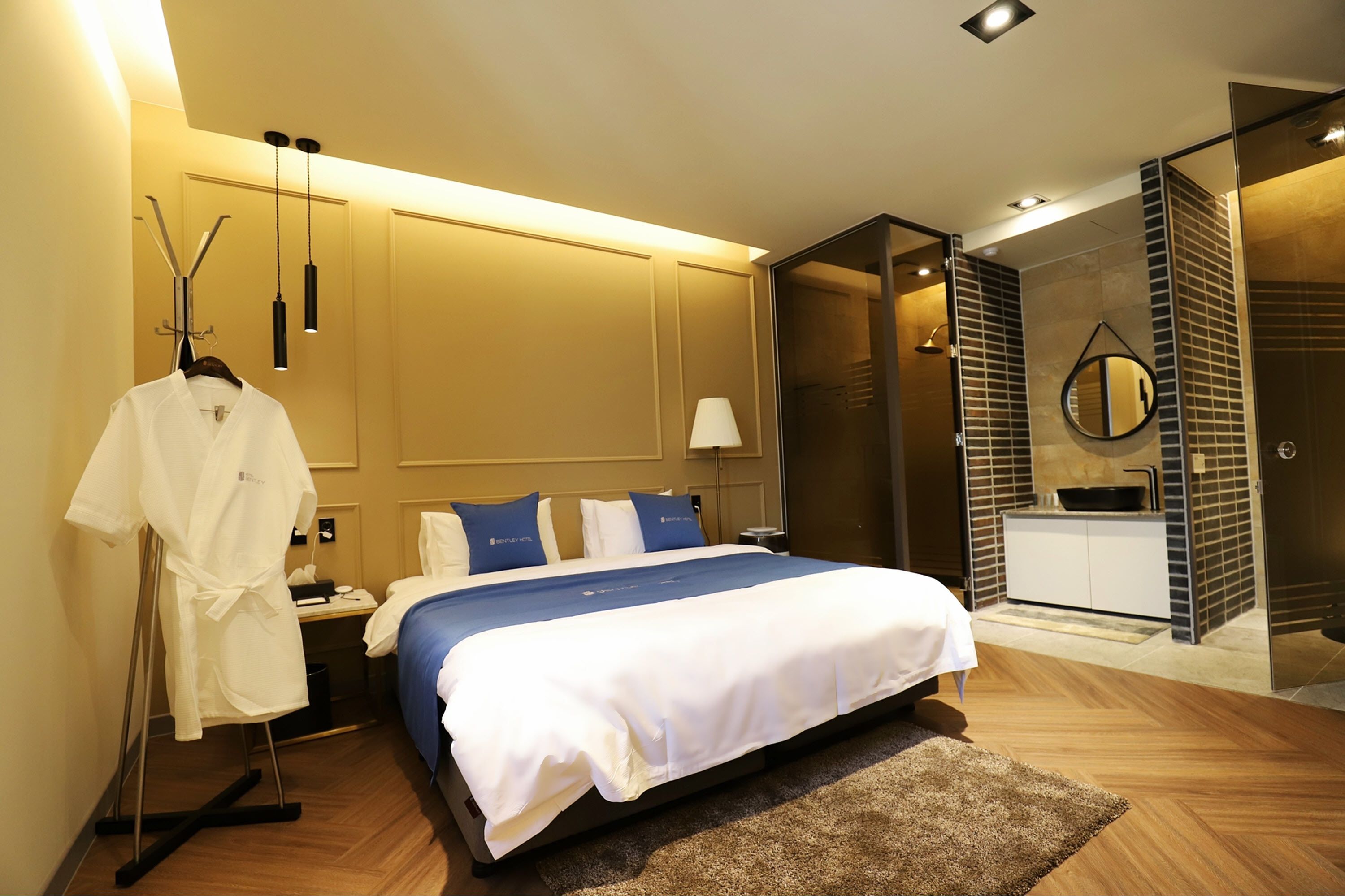 Une chambre d’hôtel moderne dotée d’un grand lit, de tables de chevet, d’un porte-peignoir, d’un petit bureau et d’un dressing.