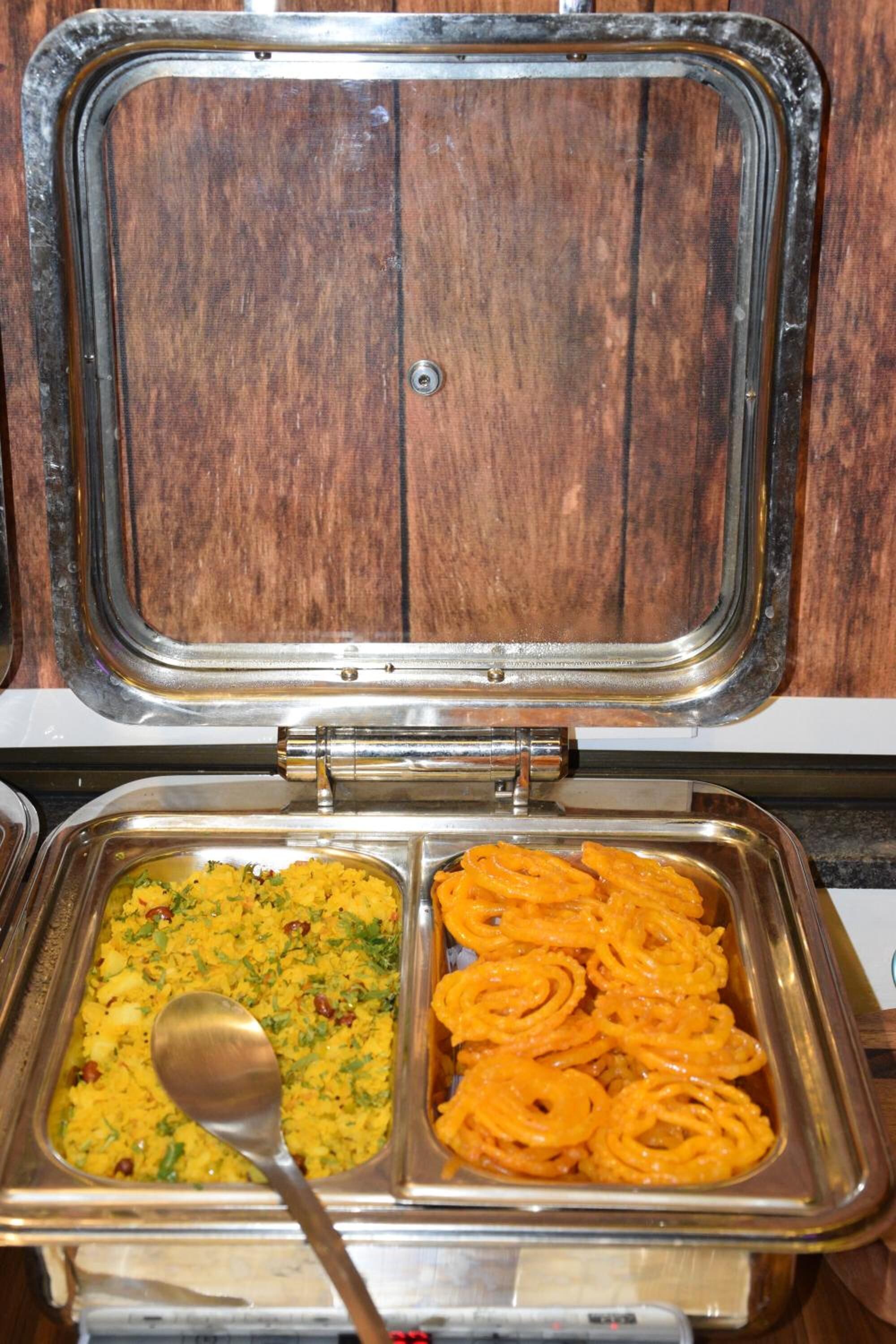 Un buffet composé de deux sections : une avec du riz jaune garni d’herbes et l’autre avec des rondelles d’oignon orange.