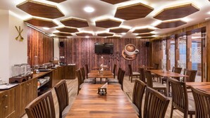 A restaurant with wooden furniture, hexagonal ceiling lights, and a coffee cup on the wall. - Hotel CityInn (Gandhinagar)