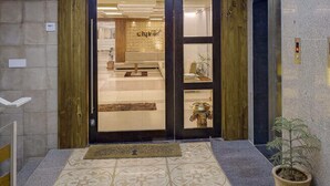 A hotel lobby with a patterned floor, a wooden door, and a ceiling skylight. - Hotel CityInn (Gandhinagar)