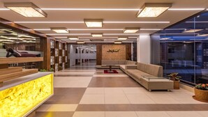A modern lobby with a reception desk, seating area, and a large window. - Hotel CityInn (Gandhinagar)